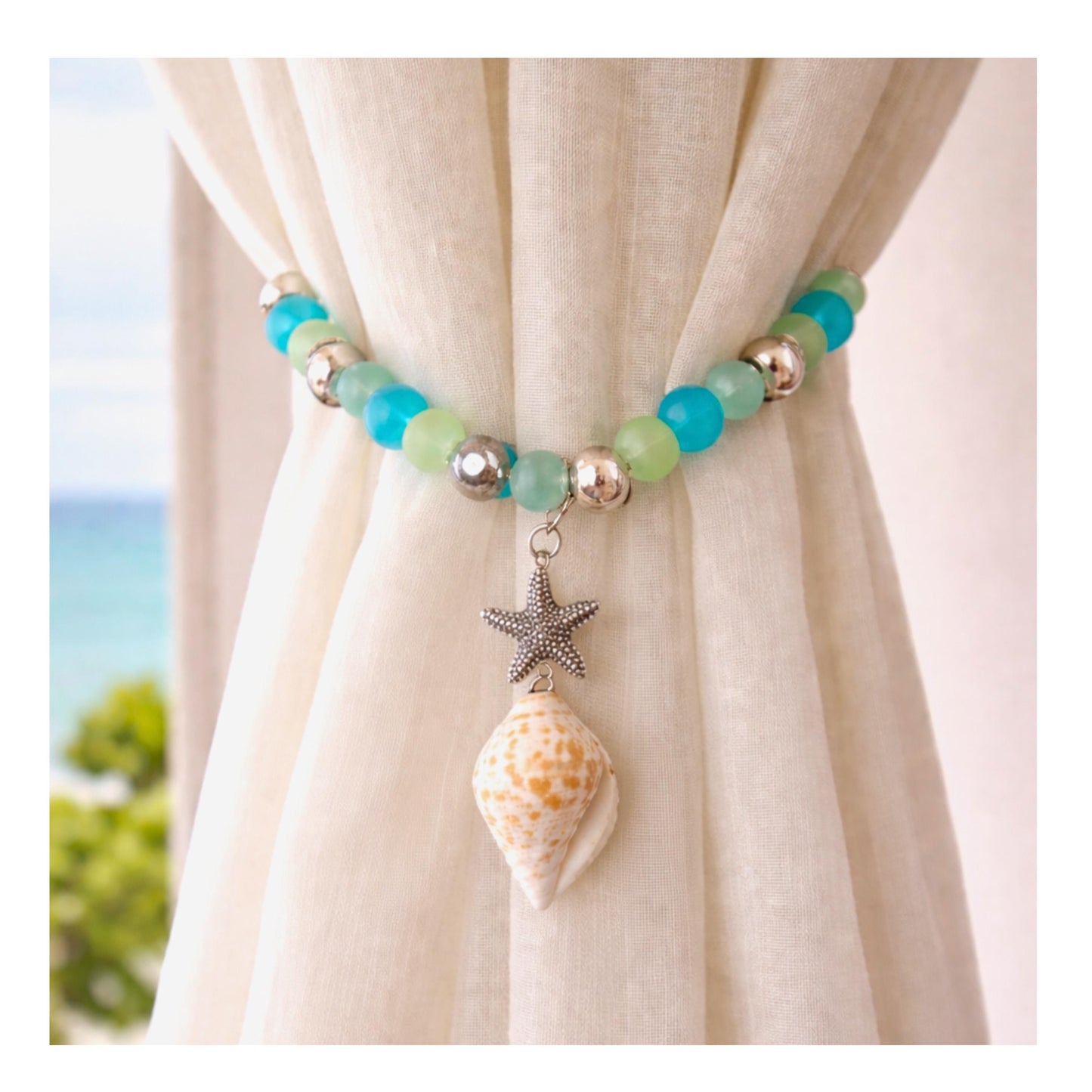 Beaded seashell curtain tiebacks shown styled on sheer curtains — handmade tropical coastal drapery holdbacks