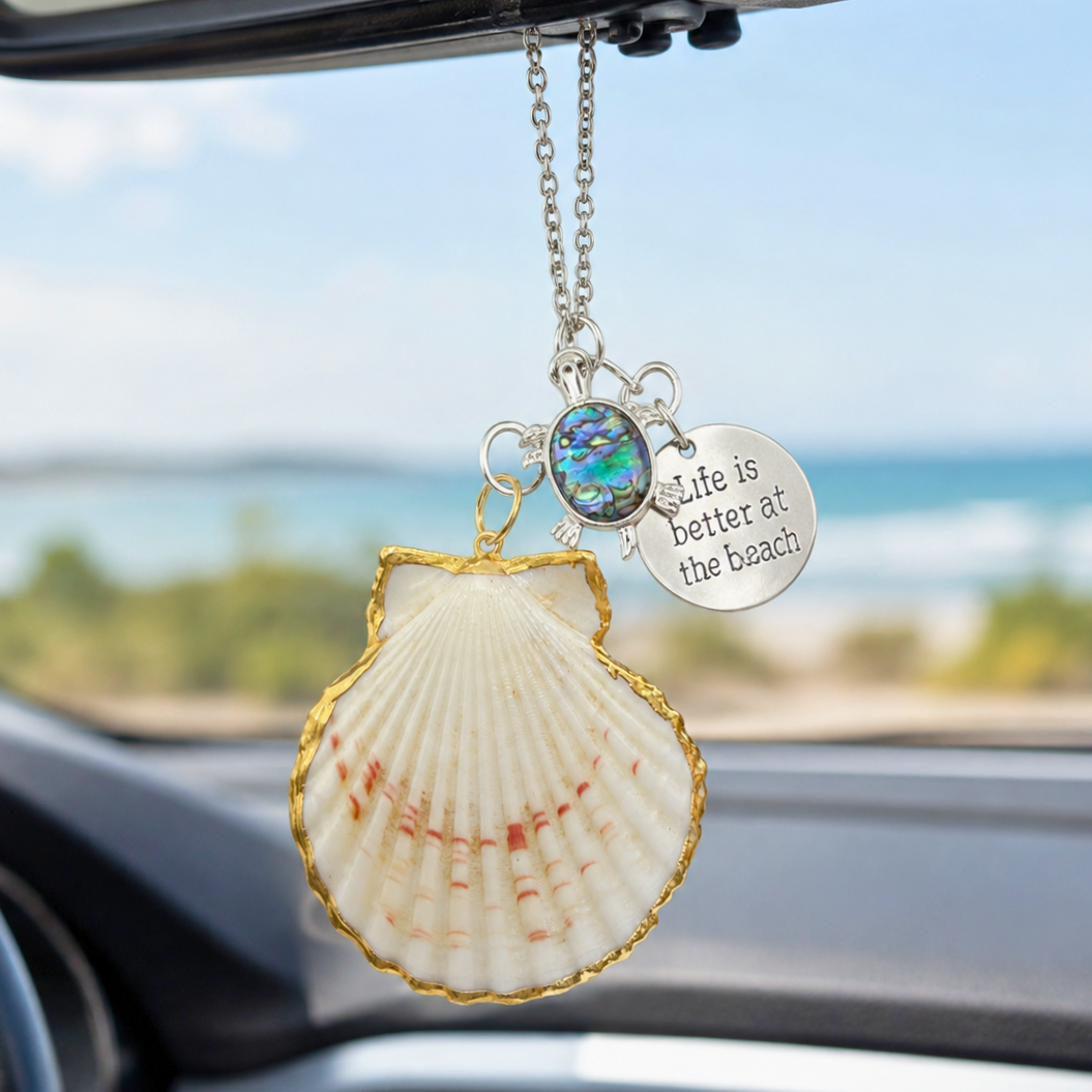 Shell-shaped car hanging ornament with 'Life is better at the beach' quote in a car interior.