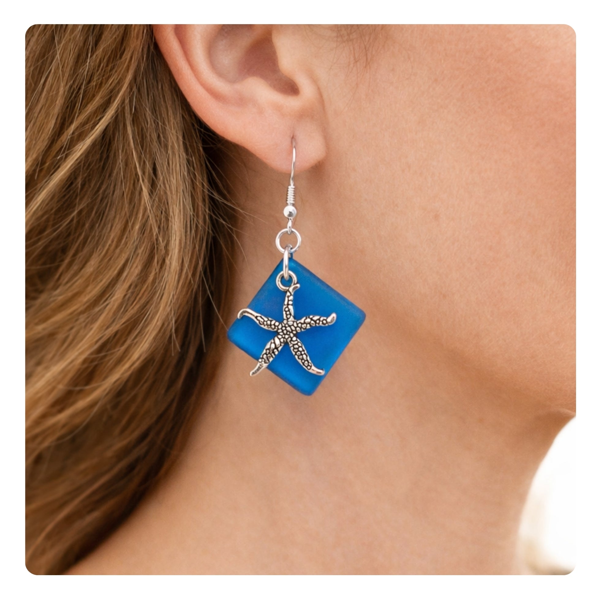 Ocean blue sea glass starfish dangle drop earrings shown on a model — handmade coastal jewelry