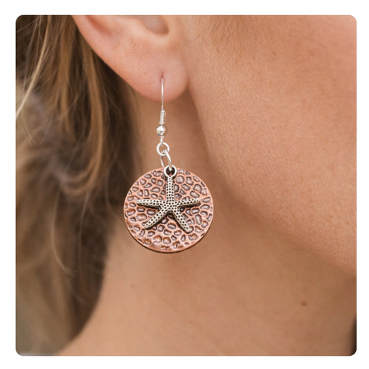 Hammered copper starfish dangle earrings shown on a model — handmade beach jewelry