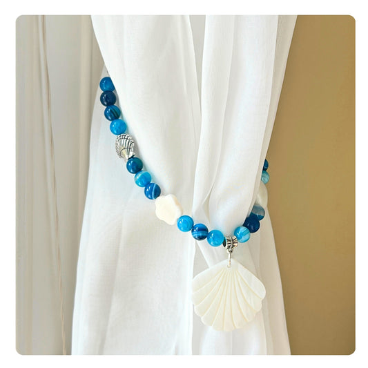 Set of two seashell curtain tiebacks shown styled on sheer curtains — handmade beach cottage home decor

